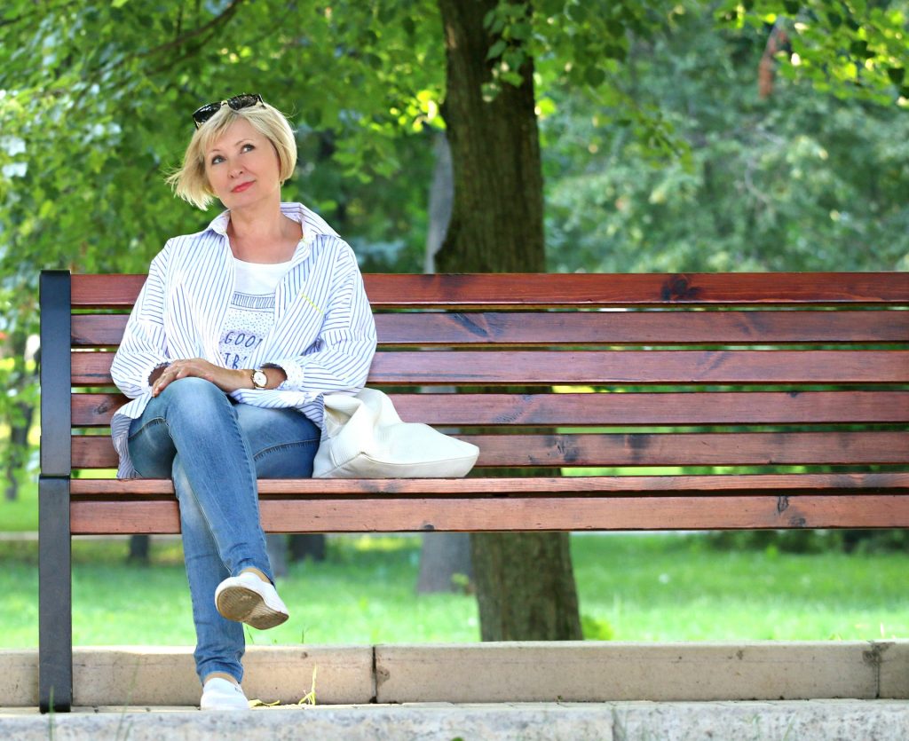 Frau sitzt alleine auf einer Parkbank